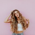 woman standing next to pink wall while scratching her head