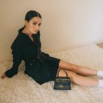 woman in black long-sleeved dress sitting on gray area rug