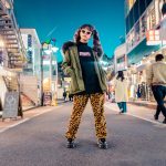 woman in green jacket stands and pose on street